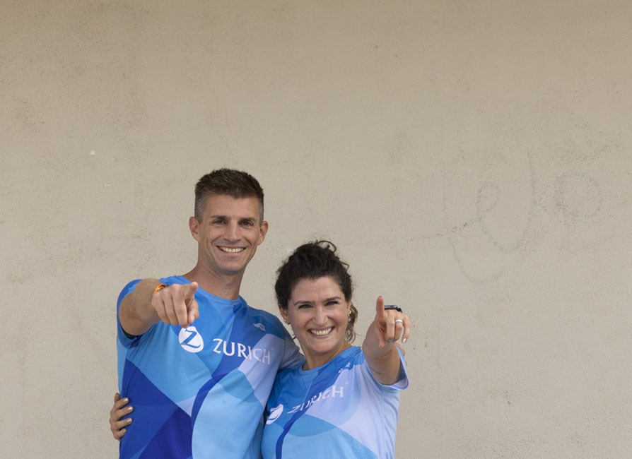 dos personas con camiseta de deporte Zurich señalando con el dedo