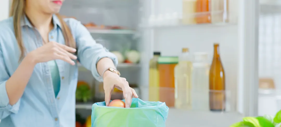 Mujer tirando alimentos del frigorífico a la basura