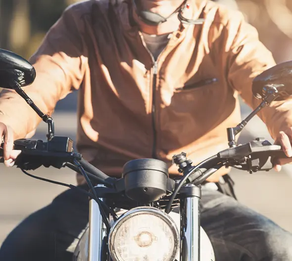 primer plano de una moto custom y un conductor con chaqueta de cuero