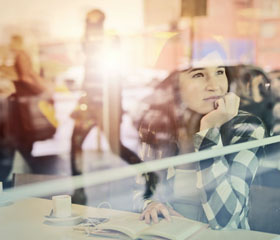 Chica mirando a través de la ventana de una cafetería